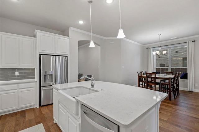 kitchen featuring decorative backsplash, stainless steel appliances, pendant lighting, white cabinets, and an island with sink