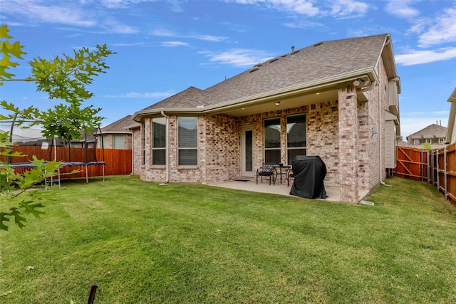 back of property featuring a yard, a trampoline, and a patio area