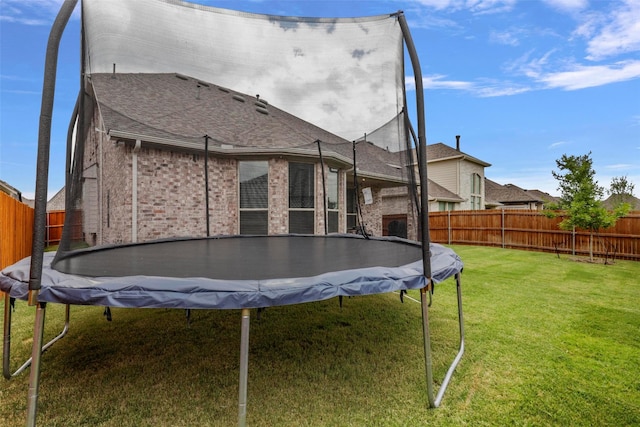 back of house featuring a yard and a trampoline