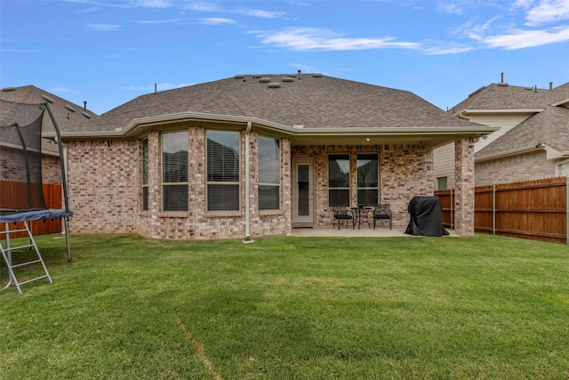 back of house with a lawn, a trampoline, and a patio