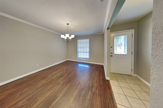 foyer featuring light hardwood / wood-style floors, a chandelier, a textured ceiling, and ornamental molding