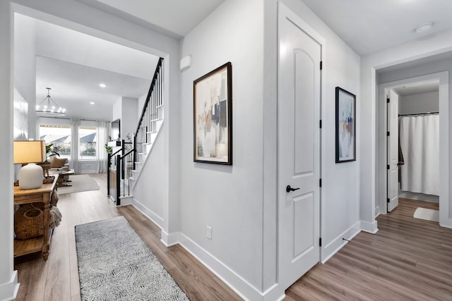 corridor with hardwood / wood-style floors and a chandelier