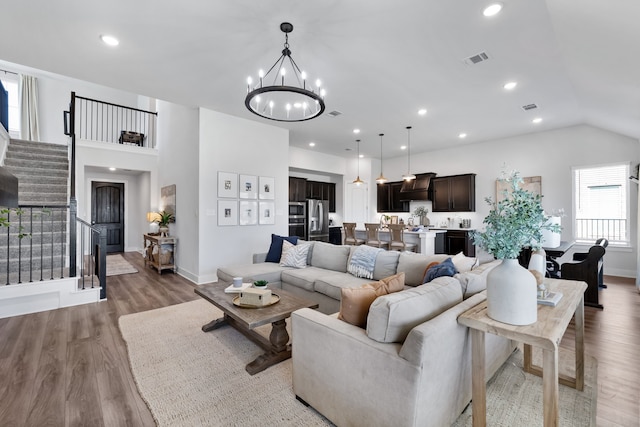 living room with a notable chandelier, wood-type flooring, and vaulted ceiling