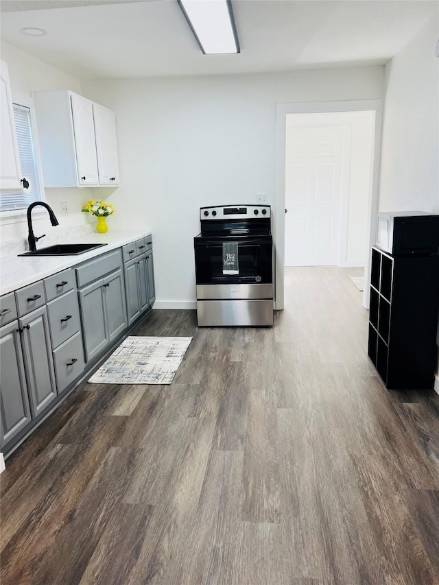 kitchen featuring gray cabinets, white cabinetry, sink, and stainless steel range with electric cooktop