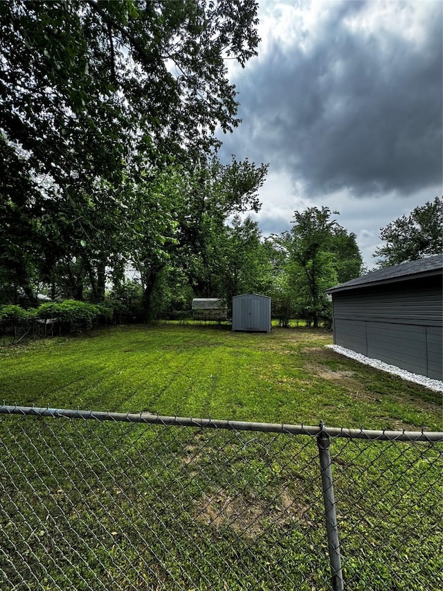 view of yard featuring fence, a storage unit, and an outbuilding