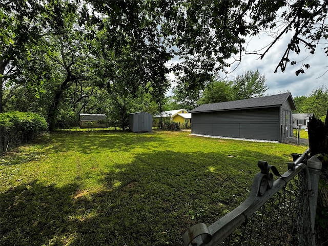 view of yard featuring a storage shed, fence, and an outdoor structure
