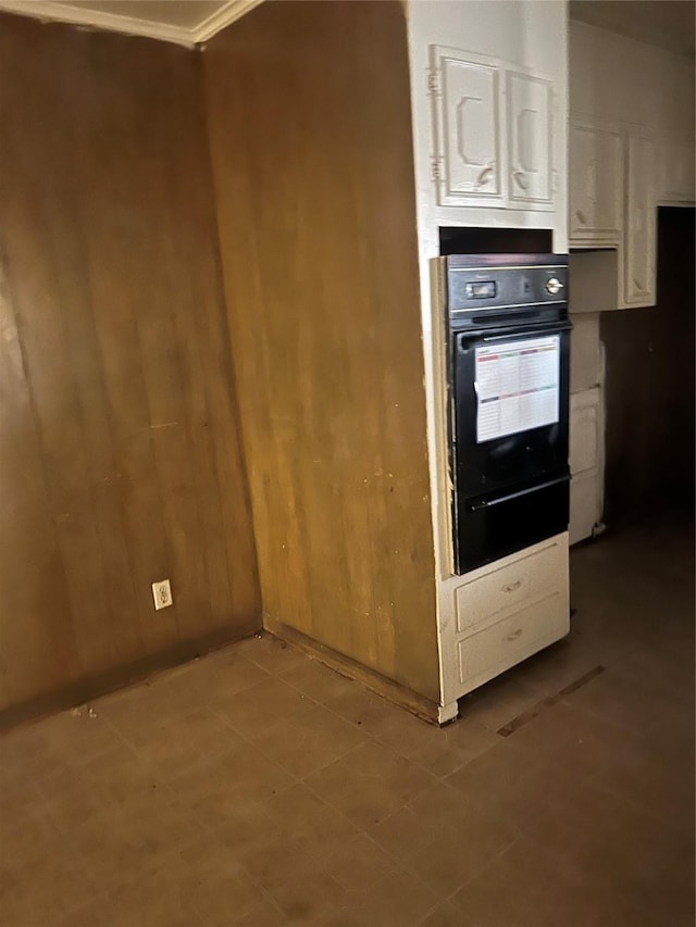 kitchen featuring black oven, wood walls, and ornamental molding