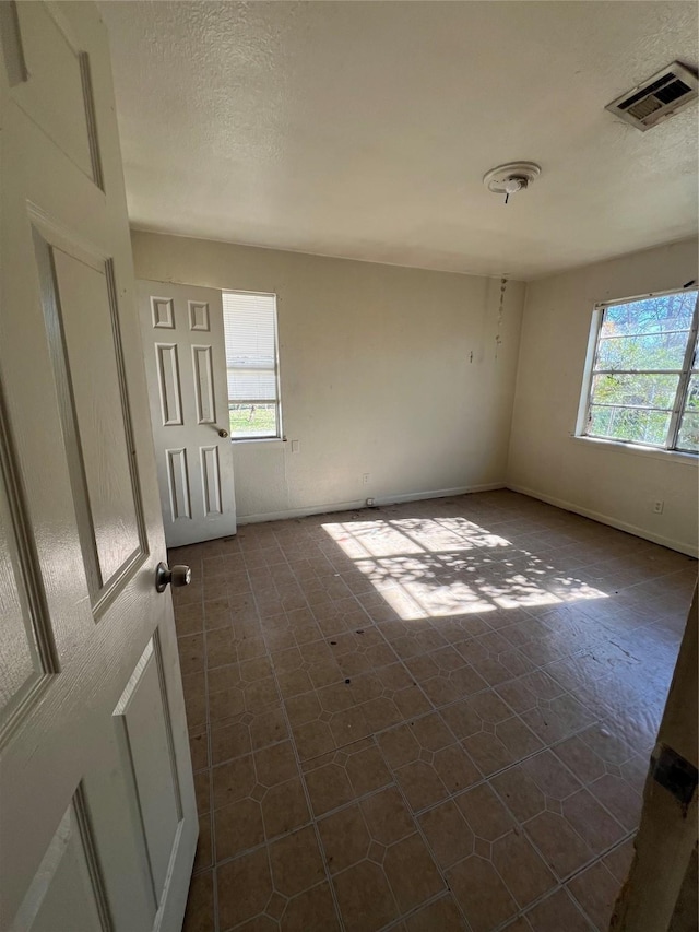 tiled spare room with a healthy amount of sunlight and a textured ceiling