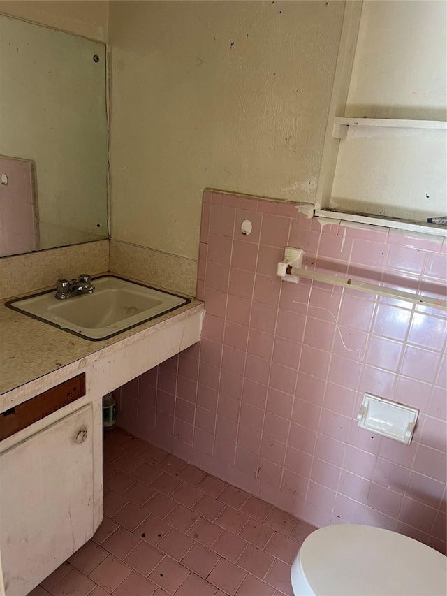 bathroom featuring toilet, tile patterned floors, tile walls, and sink