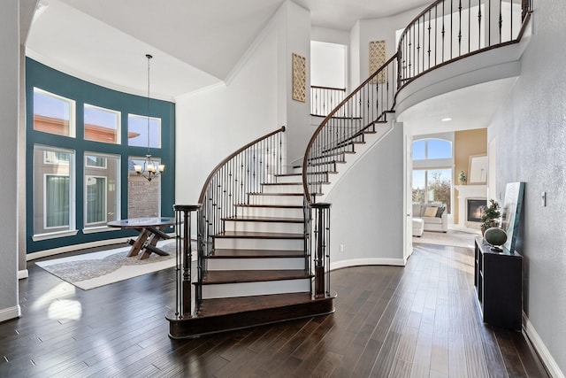 staircase featuring a chandelier, a towering ceiling, hardwood / wood-style flooring, and ornamental molding