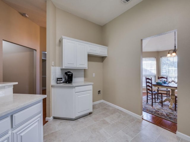 kitchen featuring tasteful backsplash, light tile patterned floors, white cabinets, a chandelier, and hanging light fixtures