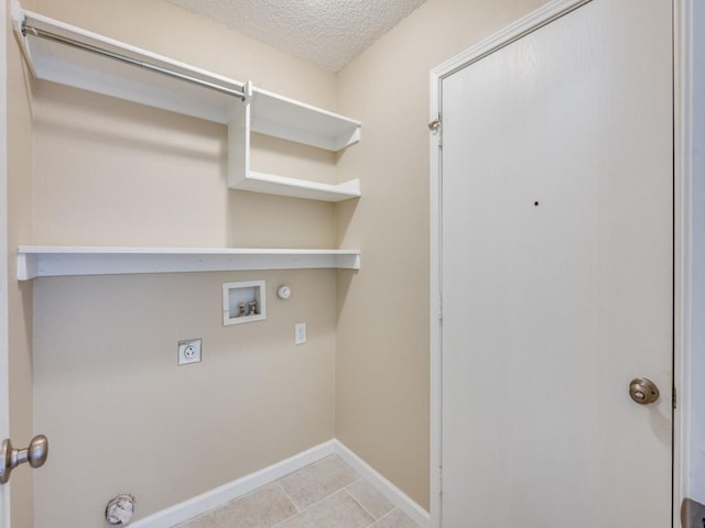 washroom with electric dryer hookup, gas dryer hookup, hookup for a washing machine, light tile patterned floors, and a textured ceiling