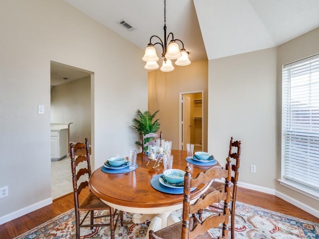 dining area featuring a chandelier, light hardwood / wood-style floors, and lofted ceiling