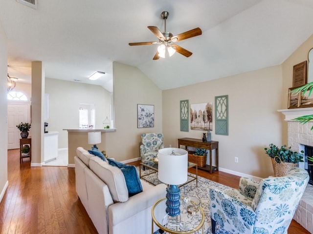 living room featuring ceiling fan, a fireplace, hardwood / wood-style floors, and lofted ceiling