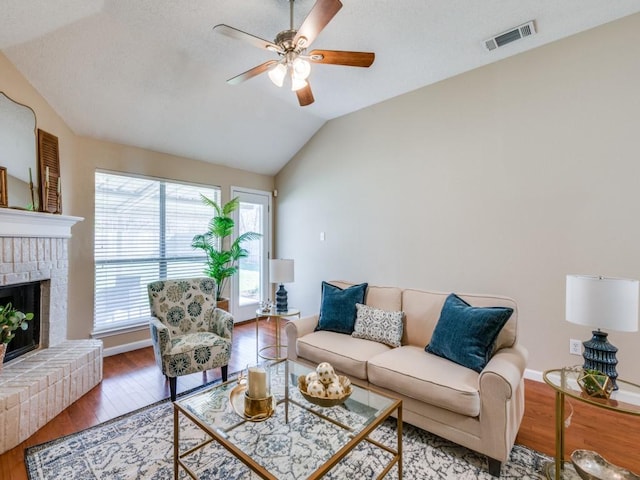 living room with a fireplace, hardwood / wood-style flooring, ceiling fan, and lofted ceiling