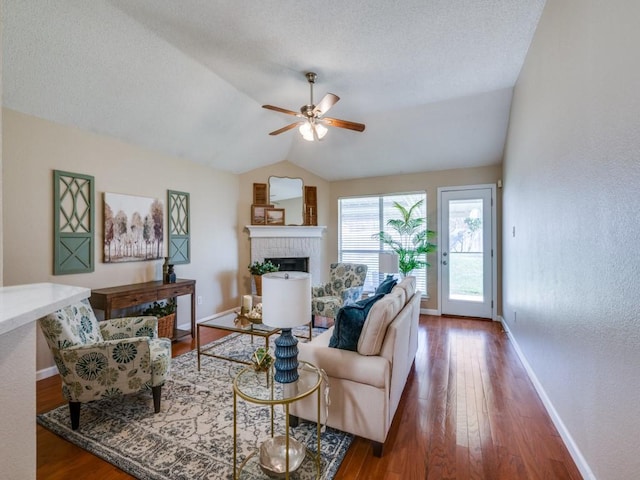 living room featuring lofted ceiling, a brick fireplace, ceiling fan, dark hardwood / wood-style floors, and a textured ceiling