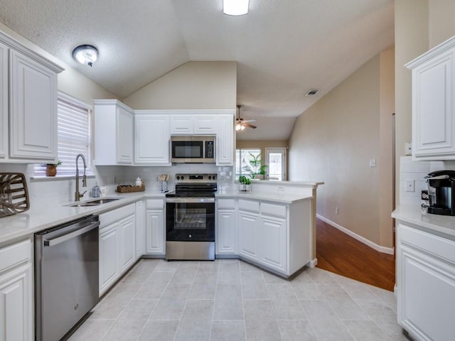 kitchen featuring white cabinets, sink, vaulted ceiling, kitchen peninsula, and stainless steel appliances