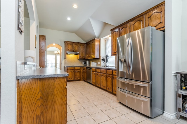 kitchen featuring a healthy amount of sunlight, tasteful backsplash, lofted ceiling, light tile patterned floors, and appliances with stainless steel finishes