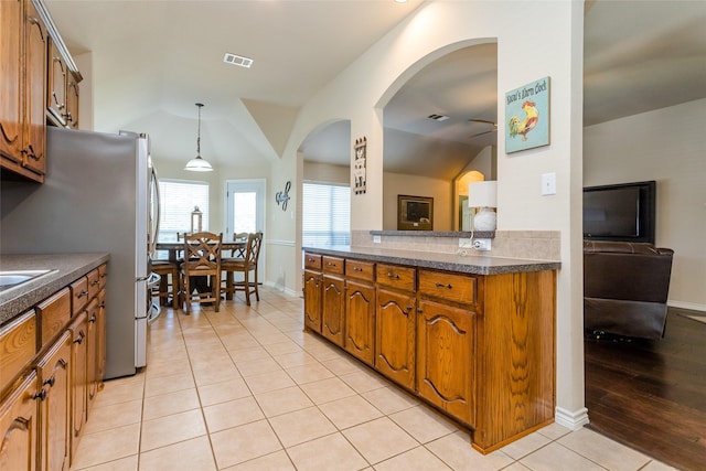 kitchen with stainless steel fridge, light tile patterned floors, and hanging light fixtures