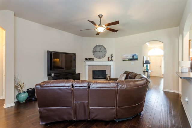 living room featuring ceiling fan, dark hardwood / wood-style floors, and a tile fireplace