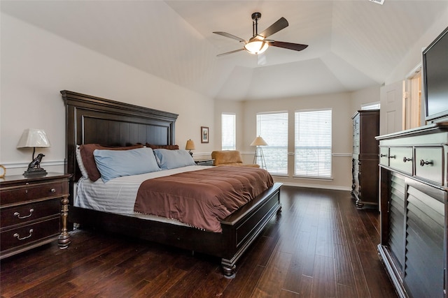 bedroom with ceiling fan, dark hardwood / wood-style flooring, a tray ceiling, and vaulted ceiling