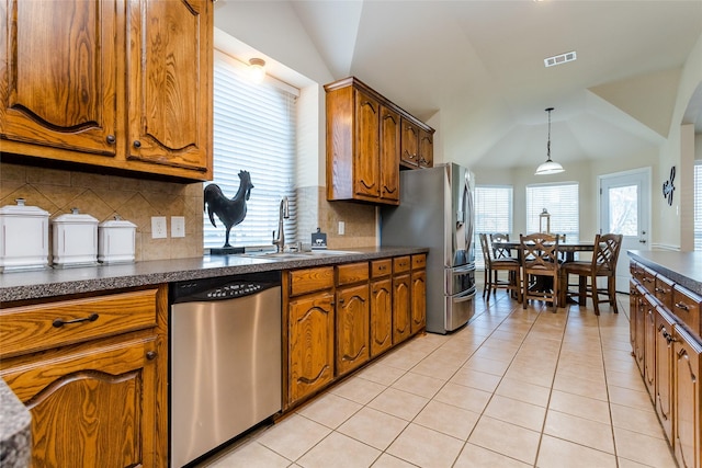 kitchen with decorative backsplash, appliances with stainless steel finishes, lofted ceiling, and sink