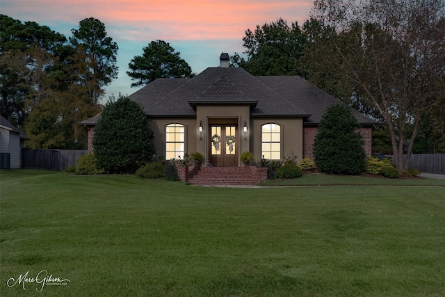 view of front facade featuring a lawn and french doors