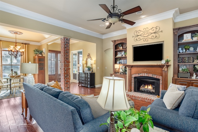 living room featuring ornate columns, dark hardwood / wood-style floors, a fireplace, ceiling fan with notable chandelier, and ornamental molding