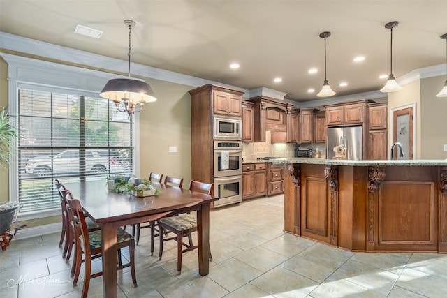 kitchen with decorative backsplash, appliances with stainless steel finishes, crown molding, an inviting chandelier, and hanging light fixtures