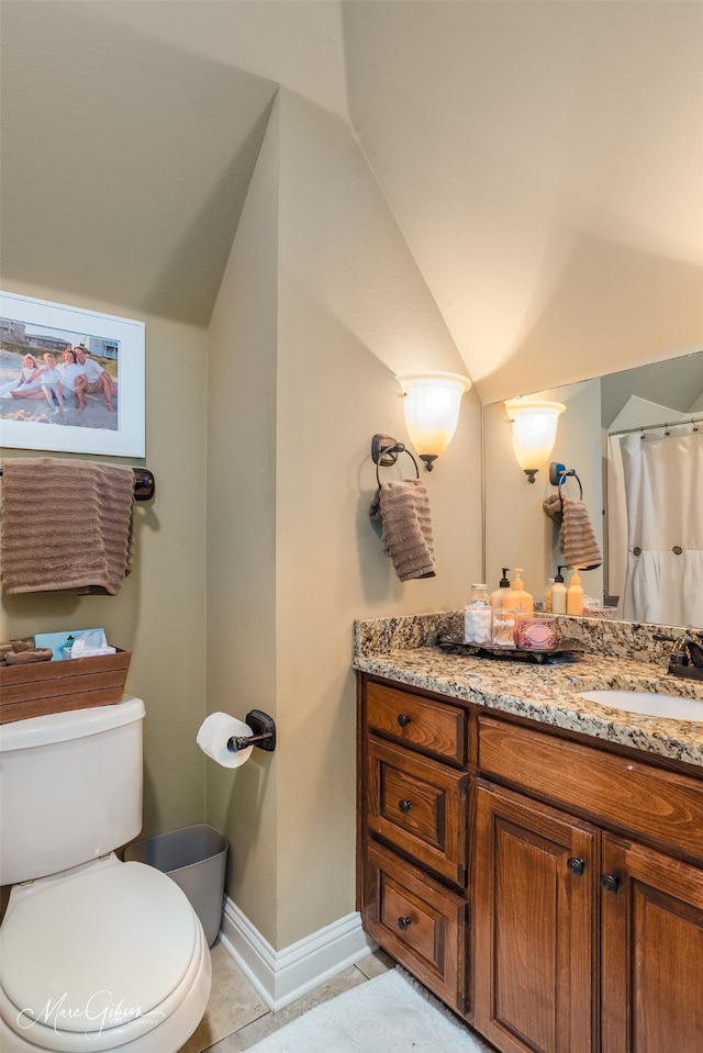 bathroom with tile patterned flooring, vanity, toilet, and vaulted ceiling