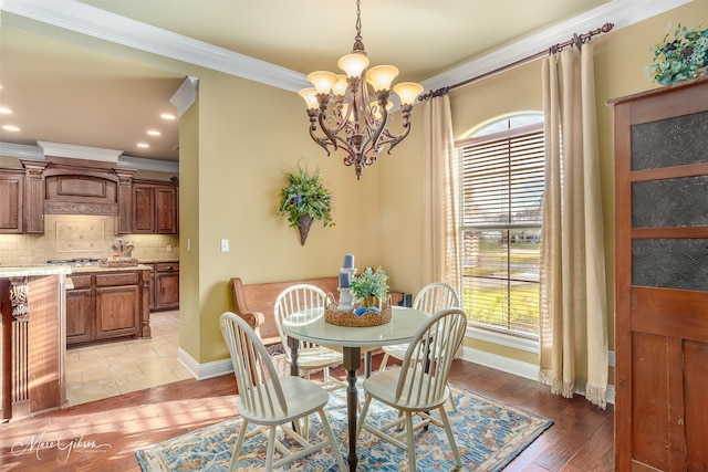 dining area with light wood-type flooring, ornamental molding, a wealth of natural light, and an inviting chandelier