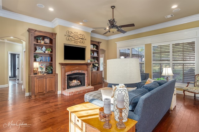 living room featuring ceiling fan, dark hardwood / wood-style flooring, ornamental molding, and a fireplace