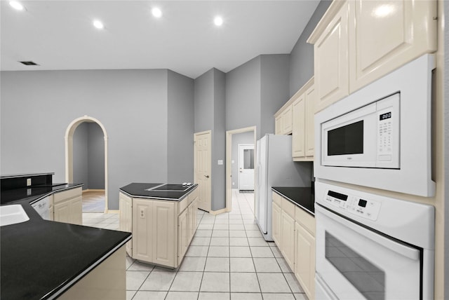 kitchen featuring cream cabinetry, light tile patterned floors, white appliances, and a kitchen island