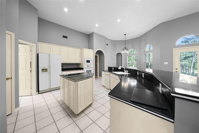 kitchen featuring light tile patterned flooring, white appliances, high vaulted ceiling, cream cabinetry, and a kitchen island