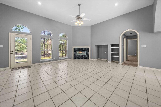 unfurnished living room featuring a towering ceiling, ceiling fan, and light tile patterned flooring