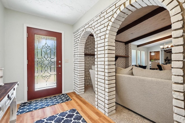 foyer featuring beam ceiling, hardwood / wood-style flooring, and a notable chandelier