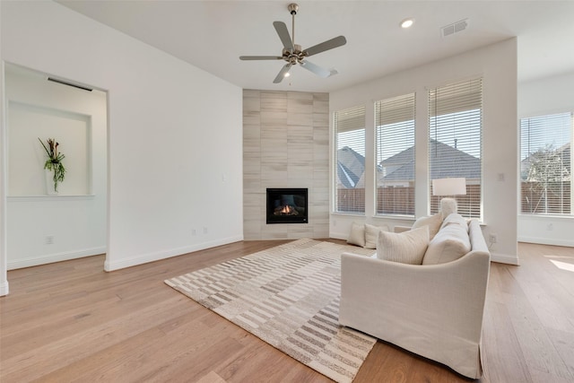 living room with ceiling fan, a fireplace, and light hardwood / wood-style flooring