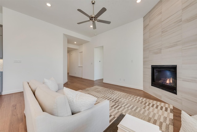 living room featuring a fireplace, wood-type flooring, and ceiling fan