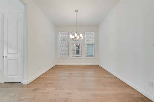 unfurnished dining area featuring a notable chandelier and light hardwood / wood-style floors