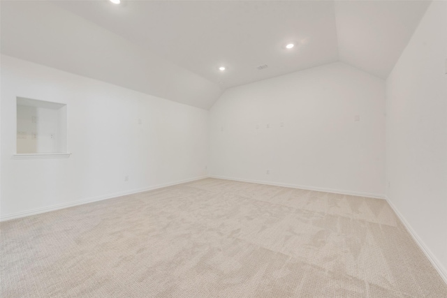 spare room with light carpet and vaulted ceiling