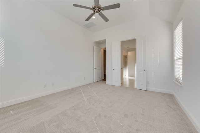 unfurnished bedroom with multiple windows, ceiling fan, light colored carpet, and lofted ceiling