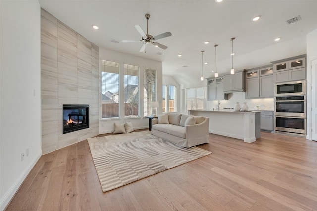 unfurnished living room with ceiling fan, light hardwood / wood-style flooring, and a tiled fireplace