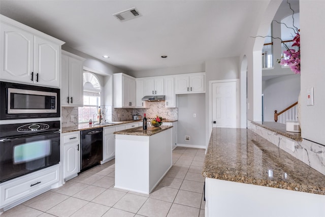 kitchen featuring dark stone counters, sink, black appliances, a center island, and white cabinetry