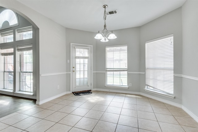 doorway with a chandelier and light tile patterned floors