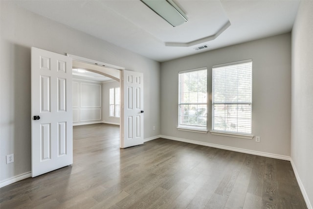 unfurnished room featuring wood-type flooring and a raised ceiling