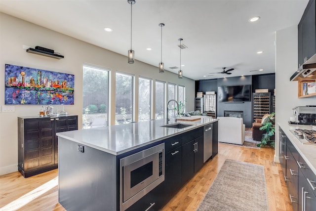 kitchen featuring ceiling fan, sink, decorative light fixtures, a center island with sink, and appliances with stainless steel finishes