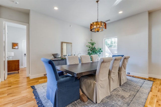 dining room with light hardwood / wood-style flooring and an inviting chandelier