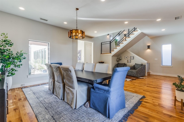 dining space with light hardwood / wood-style floors and an inviting chandelier