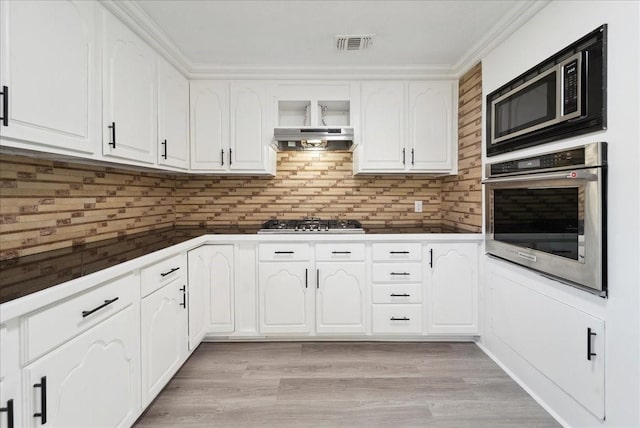 kitchen with appliances with stainless steel finishes, white cabinetry, and exhaust hood