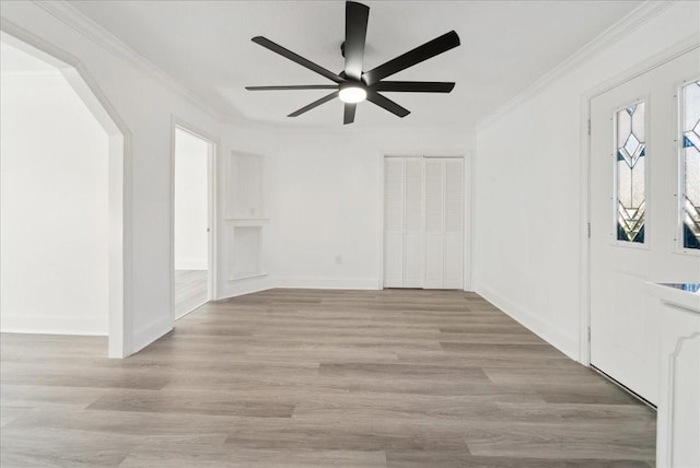 entrance foyer featuring light wood-type flooring, ceiling fan, and ornamental molding